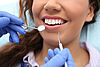 Zahnarzt untersucht die Zähne einer Frau mit Mundspiegel und Kratzer