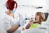 Zahnärztin erklärt Kind korrektes Zähneputzen